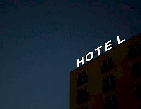 The image shows the top part of a building with a sign that reads "HOTEL" at night, with some letters unlit.